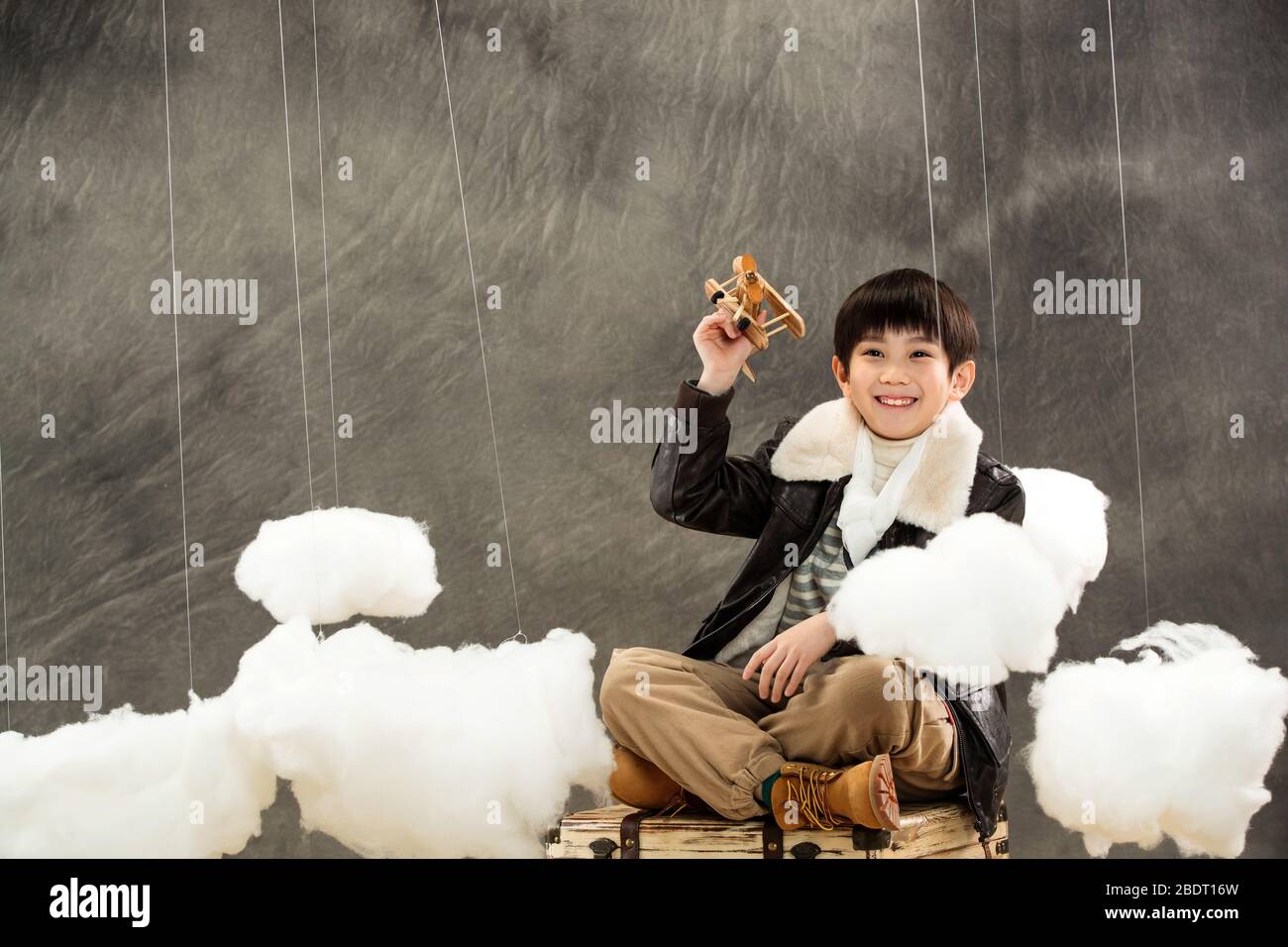 Holding a model plane boy sitting on the suitcase Stock Photo