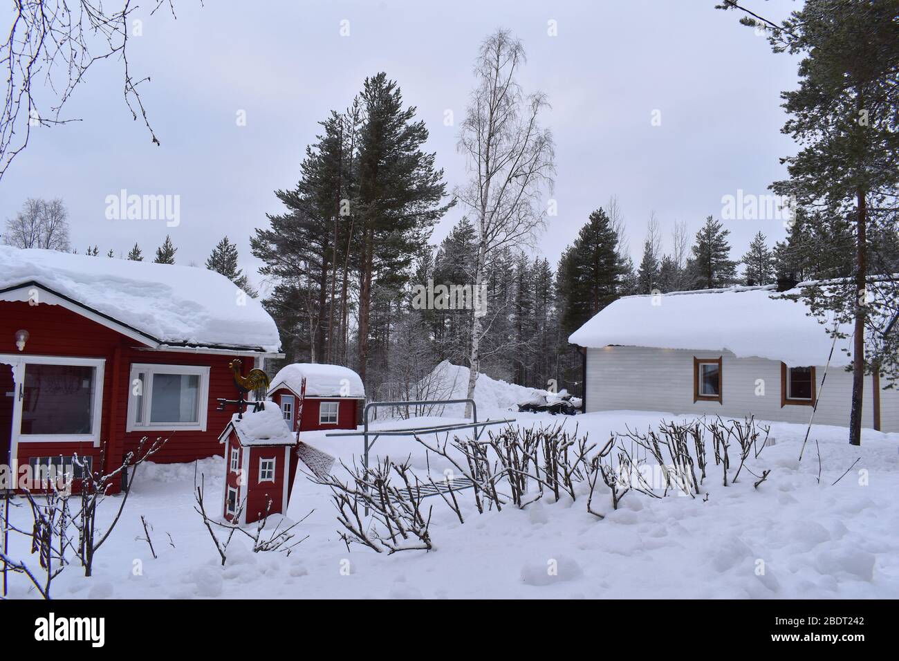 Fluffy snow covered traditional wooden Lappish holiday cottages. Windmill shaped weather vane