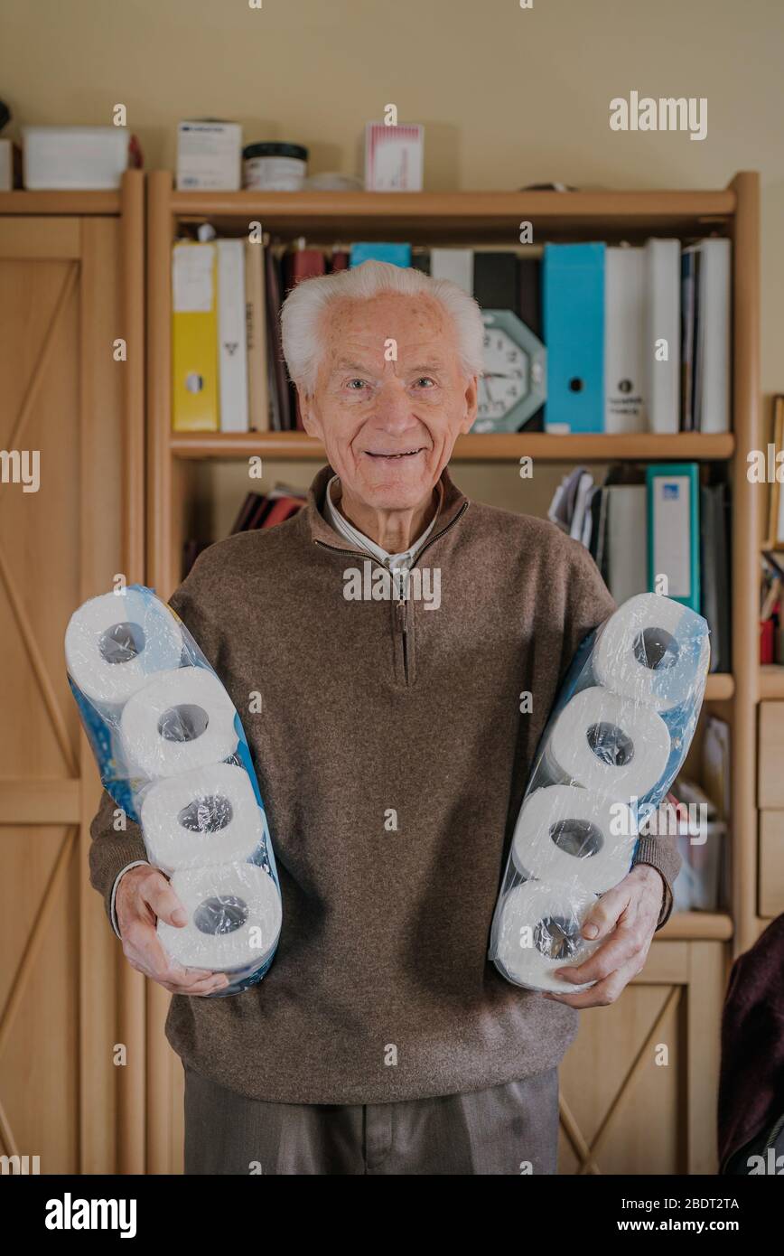 Old man holding two packs of toilet paper Stock Photo