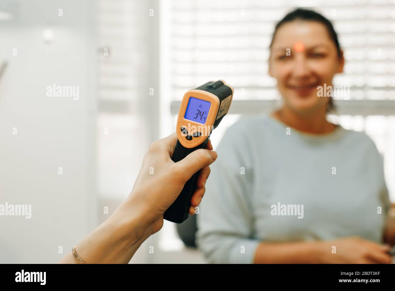 A Doctor checking a woman's temperature with a censor thermometer check