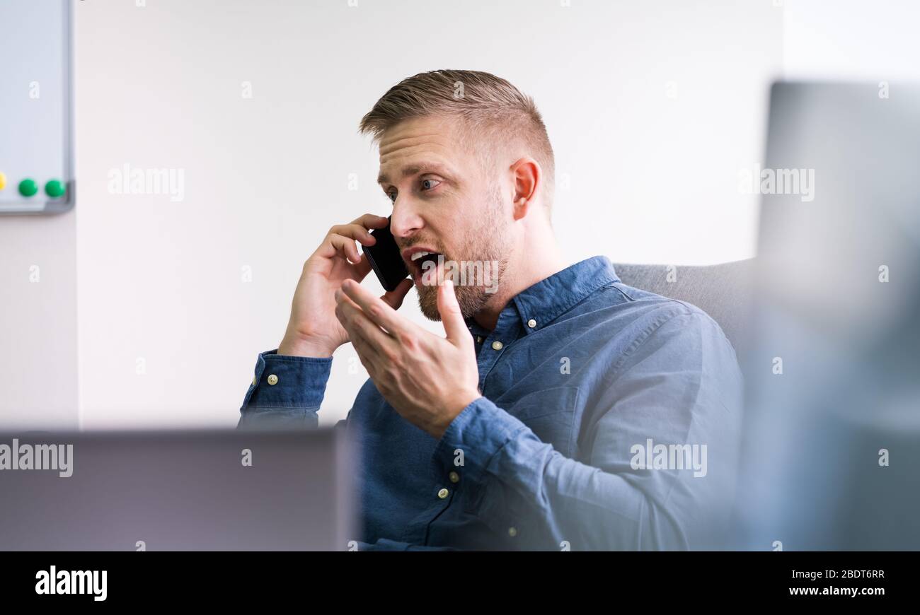 Angry Man Screaming On Phone In Office Stock Photo
