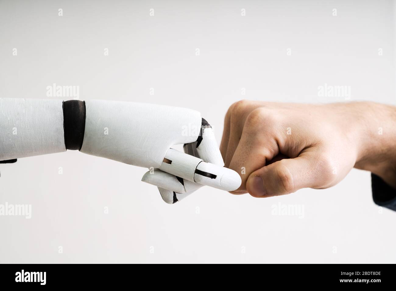 Robot And Human Hand Making Fist Bump On Grey Background Stock Photo