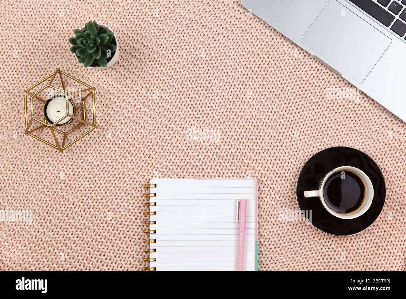Work from home concept. Modern female working space, top view. Laptop, cactus, candle, coffee, notebook on knitted blanket, copy space, flat lay. Desk Stock Photo
