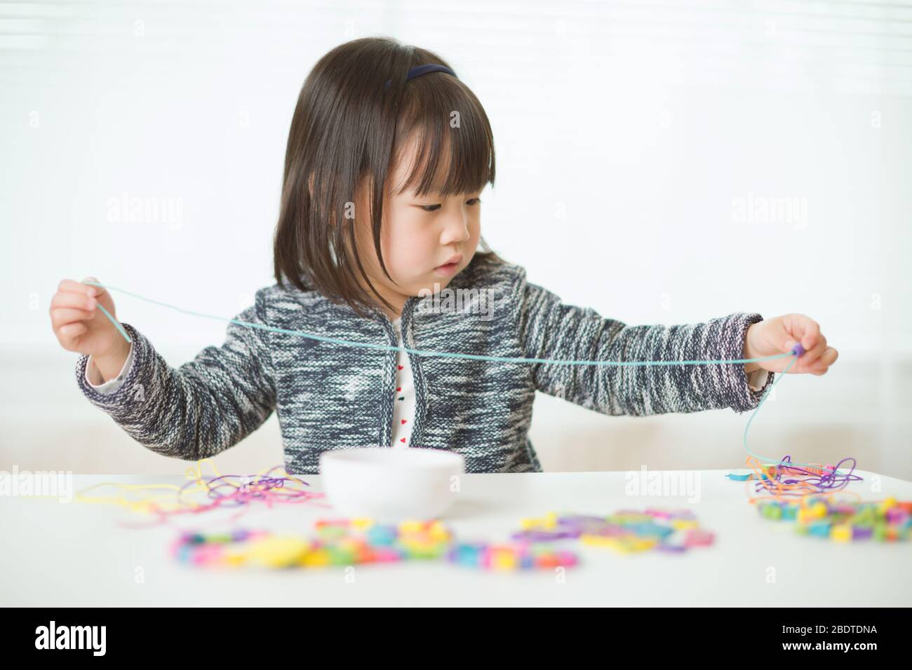 toddler girl string wooden bead crafts for homeschooling Stock Photo