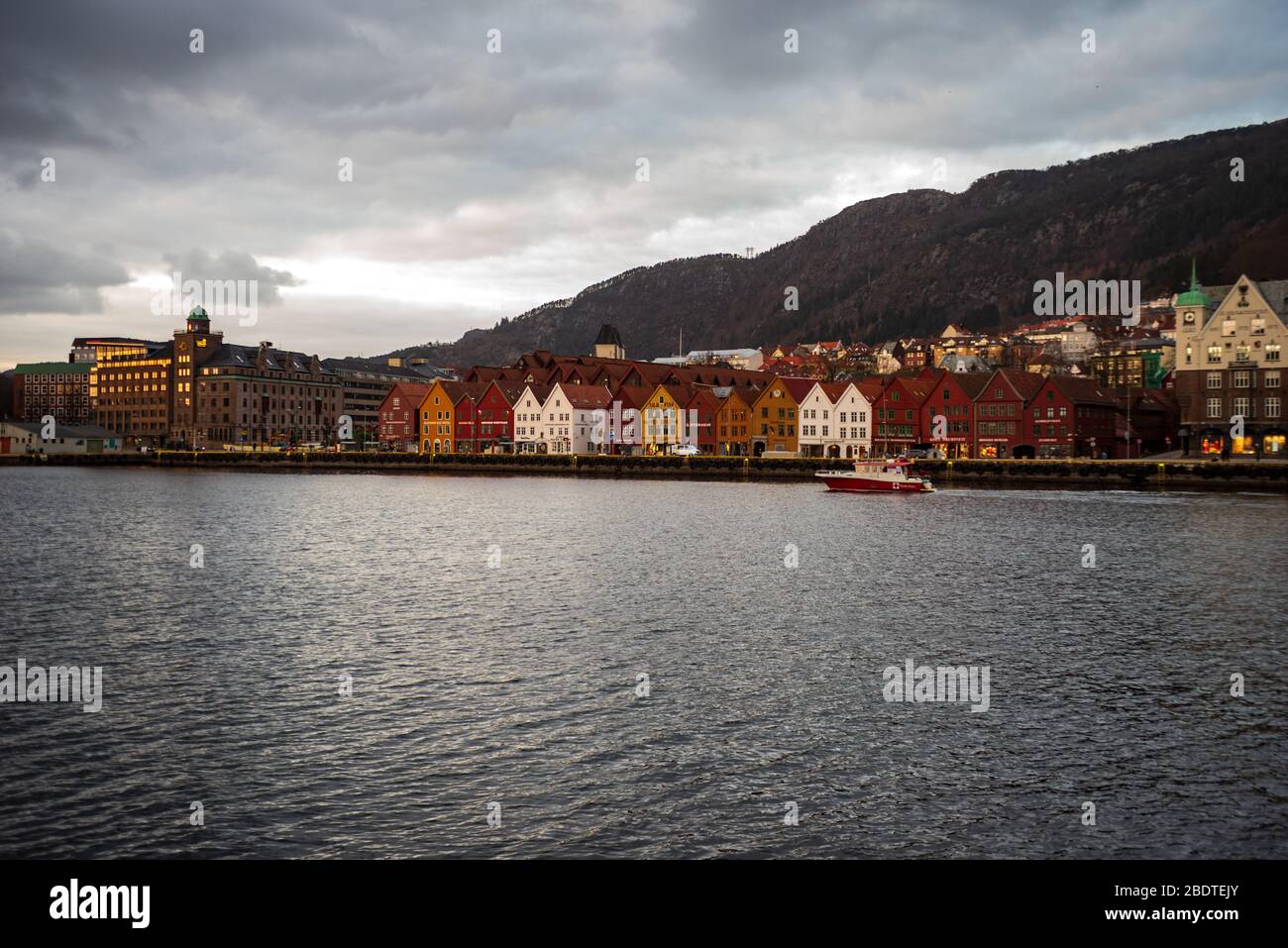 A popular tourist destination Bryggen in Bergen, Norway empty during the covid-19 epidemic. A Red Cross Charity boat can be seen leaving the harbour. Stock Photo