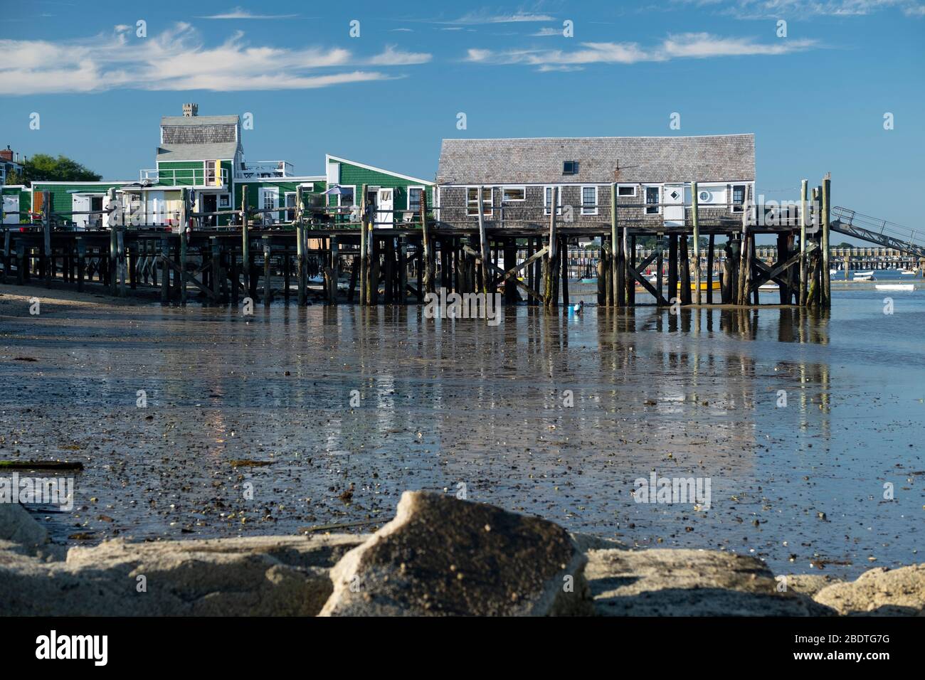 Historic old pier on Provincetown harbor reflected at low tide on Cape