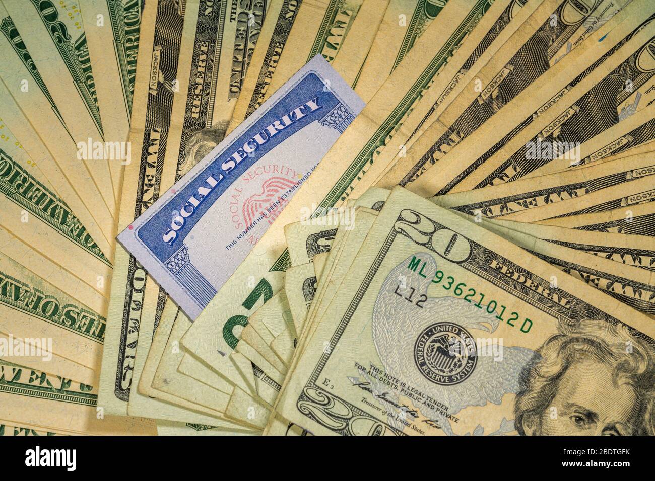 Thousands of US dollars laid out in a flat background perspective with the focus on a social security card Stock Photo