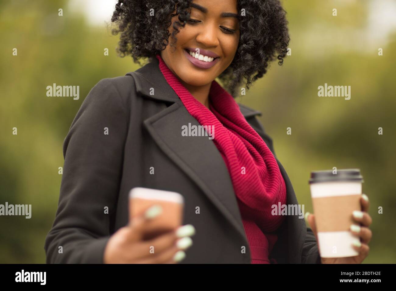 African American Woman texting and drinking coffee. Stock Photo