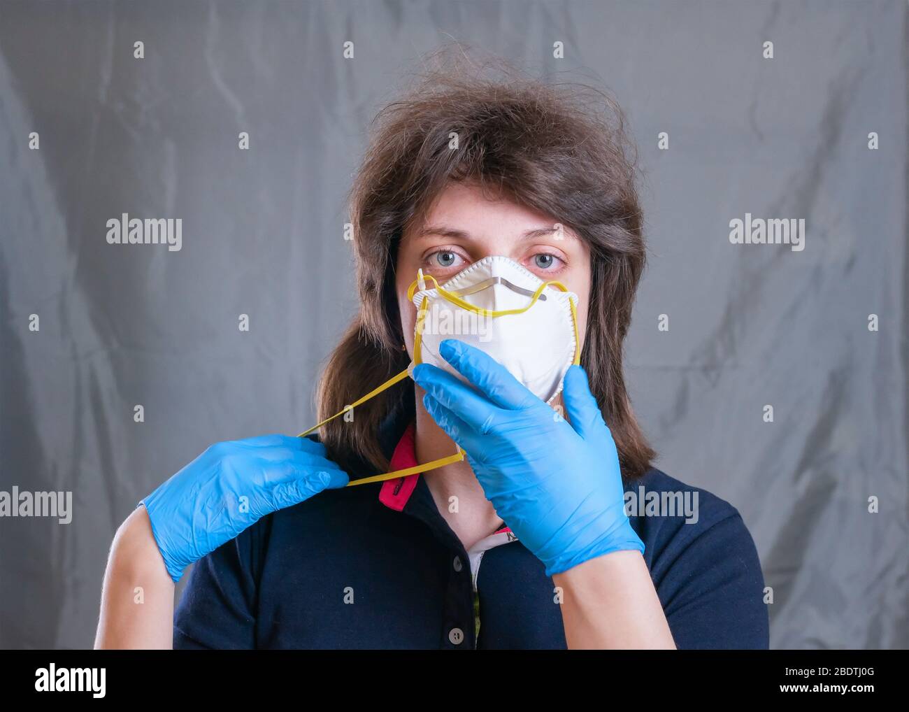 Young woman in protective respirator mask and blue gloves during self ...