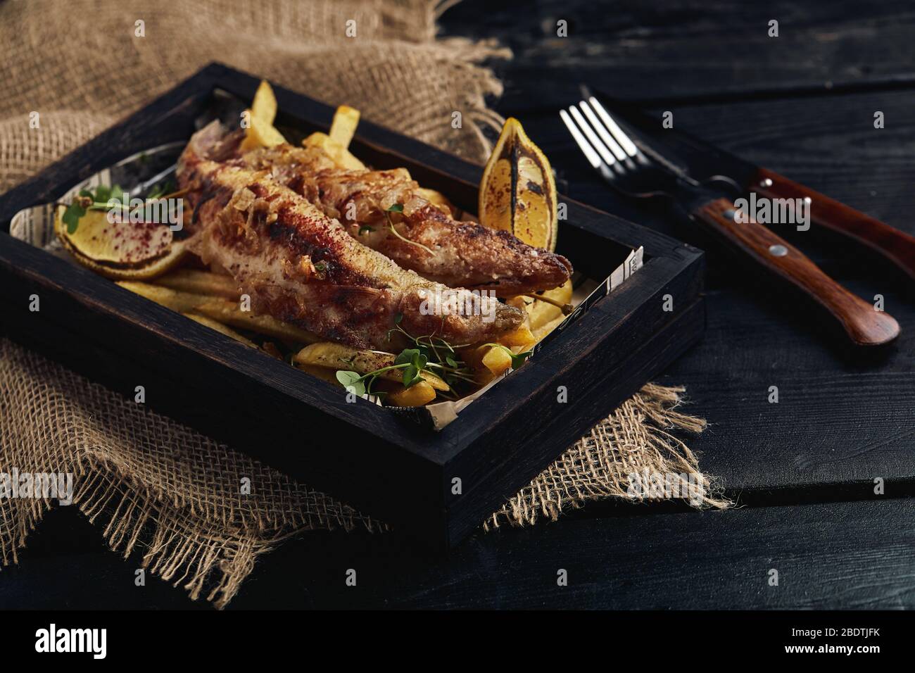 Fish and chips concept, traditional english food, fried fish and fries. Dark background, rustics style, wooden background, copy space. Stock Photo