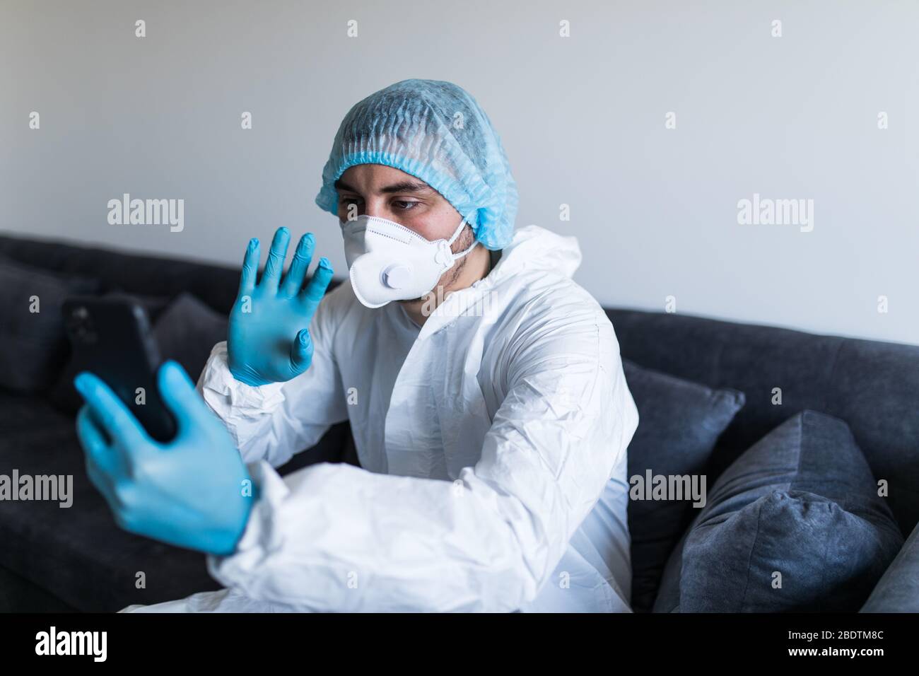 Young man in biohazard clothing make video call phone and staying at ...