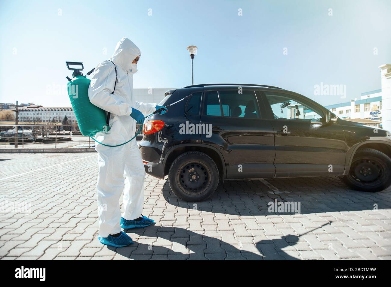 Disinfector in protective suit conducts disinfection in contaminated area of car to prevent coronavirus. Health care. Stock Photo