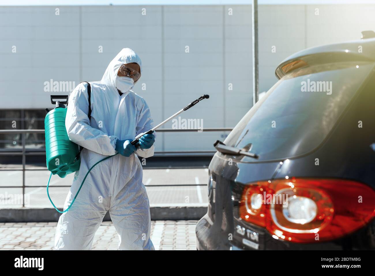 Disinfector in protective suit conducts disinfection in contaminated area of car to prevent coronavirus. Health care. Stock Photo