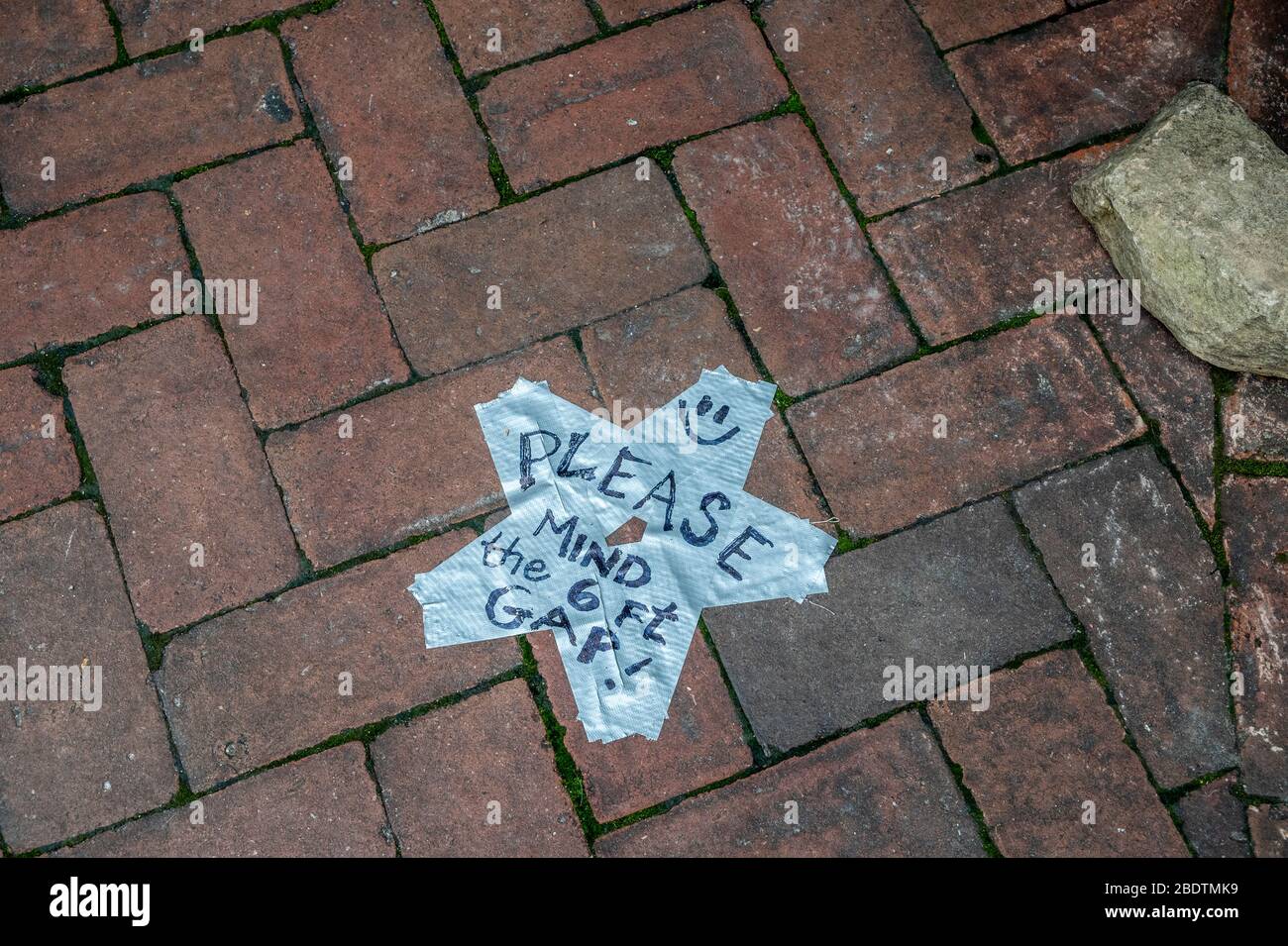 Sign on a sidewalk asking to maintain social distancing. Stock Photo