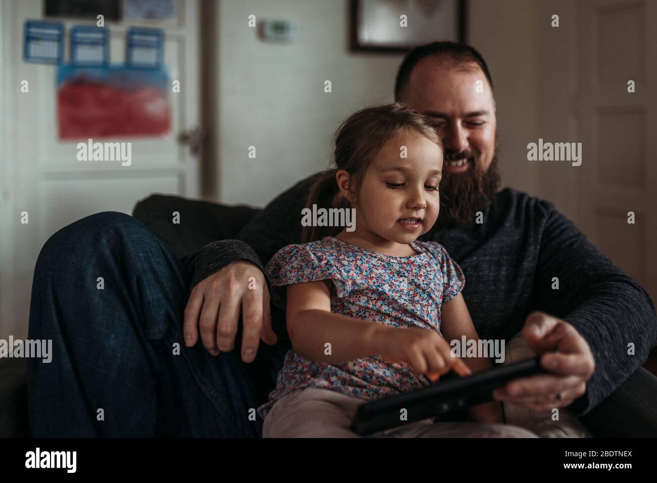 Close up of dad and young daughter playing on tablet during isolation Stock Photo