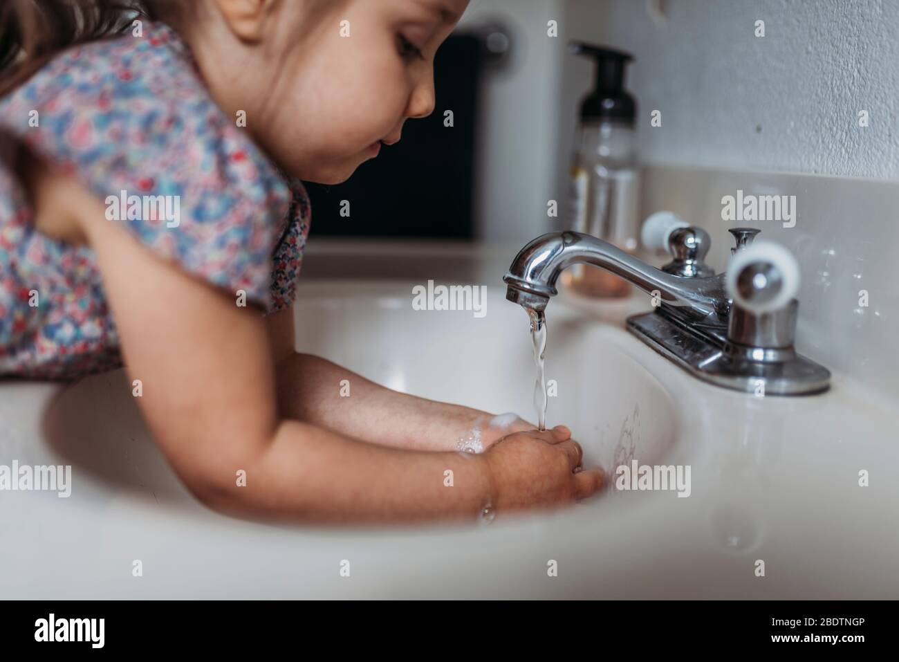 Side view of young girl washing hands in sink with soap Stock Photo - Alamy