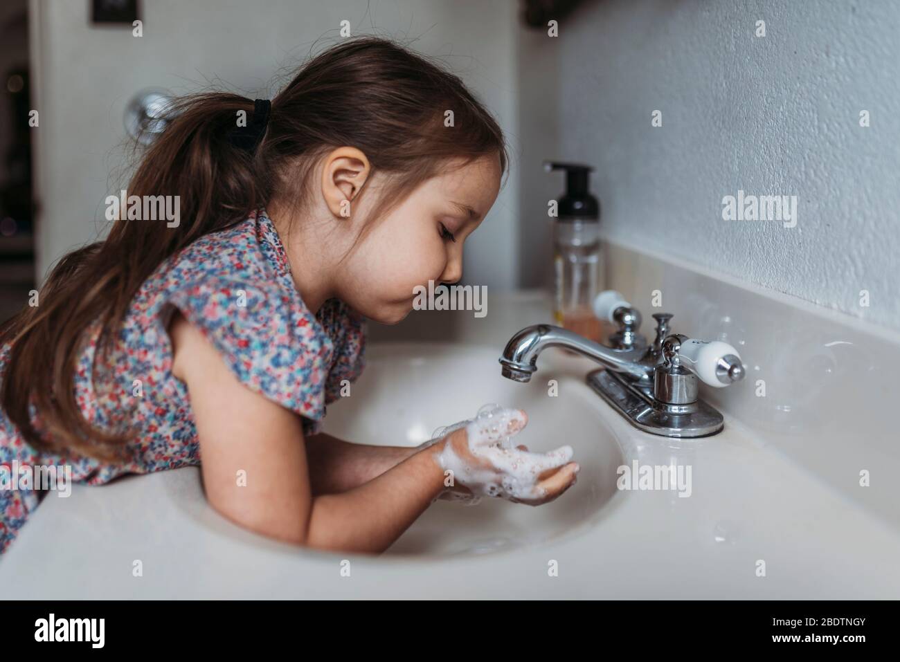 Side view of young girl washing hands in sink with soap Stock Photo - Alamy