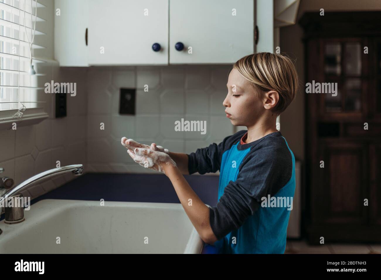 Side view of school aged boy wasking hands at home sink Stock Photo