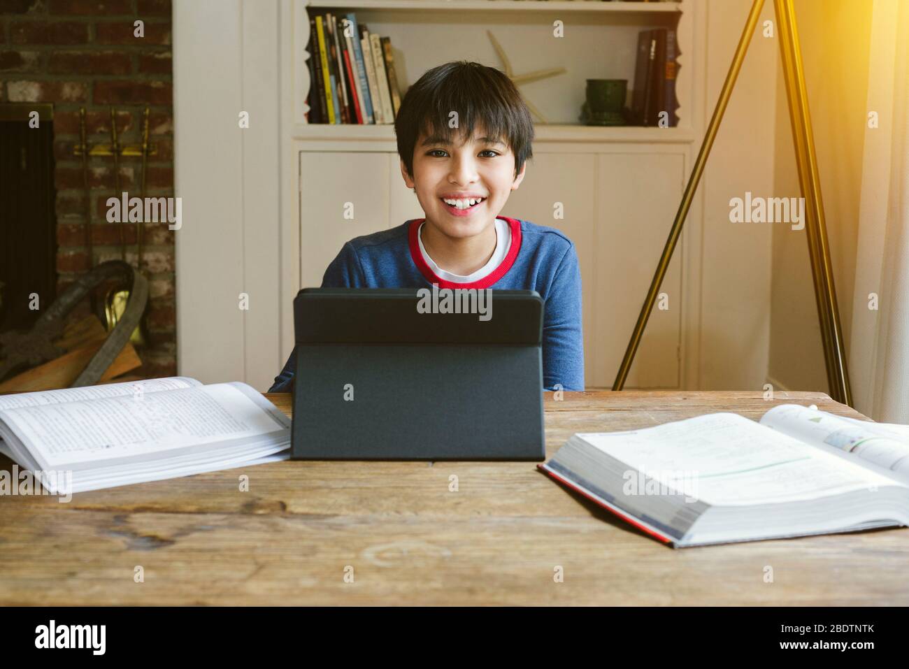Small male student is happy while being home schooled during quarantine - Books and Studies - Concept Study at Home Stock Photo