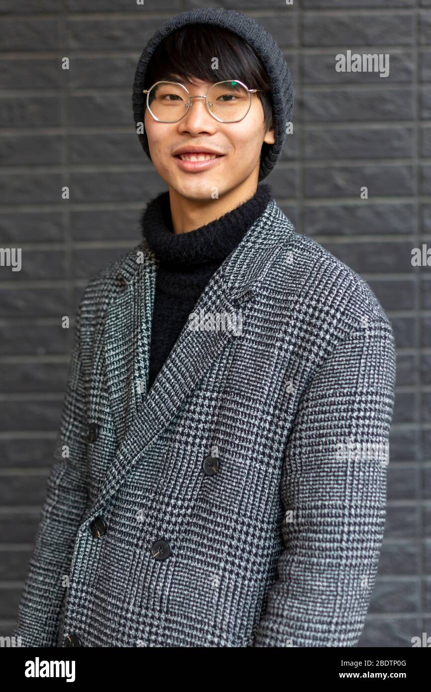 Fasionable attractive asian man wearing coat, hat, glasses smiling. Urban  city Stock Photo - Alamy