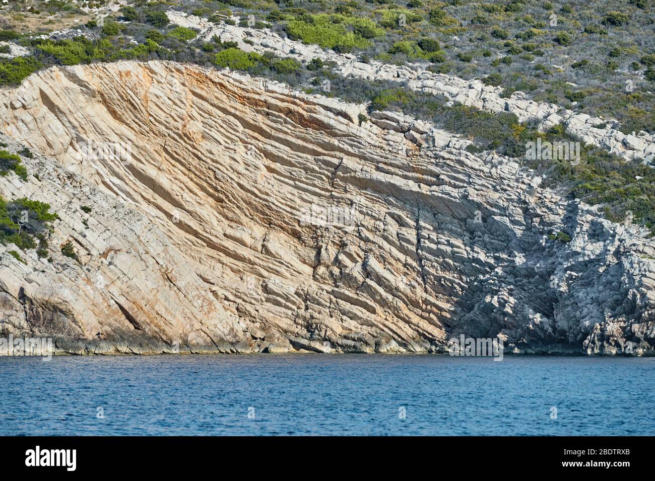 Beautiful high cliff with caves and hanging rocks of a mountain in Adriatic sea, a crevice, colorful Stock Photo