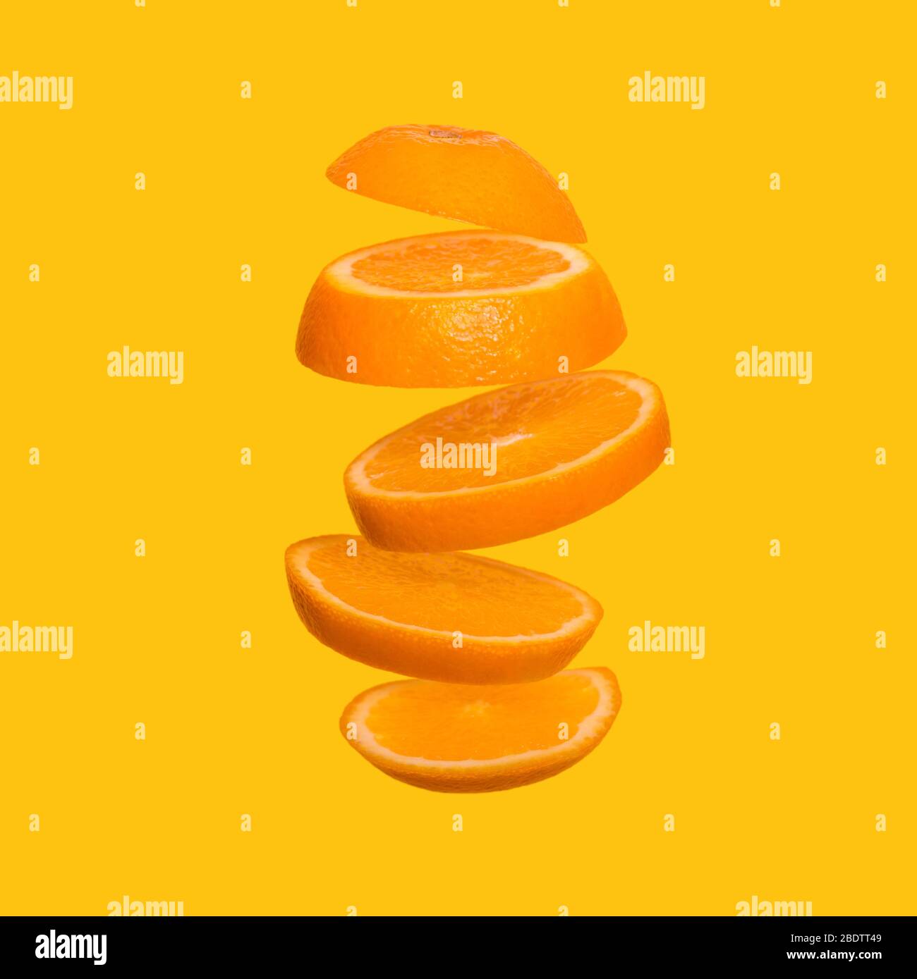 Creative concept with flying orange. Sliced orange on yellow background. Levity fruit floating in the air Stock Photo