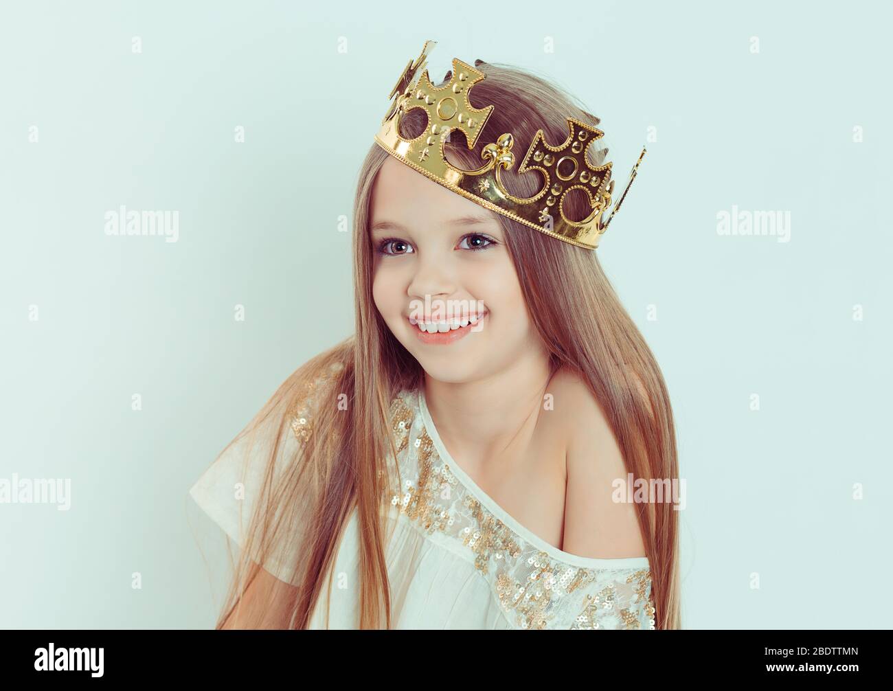 Young girl with a cute smile wearing a crown and a white dress on ...