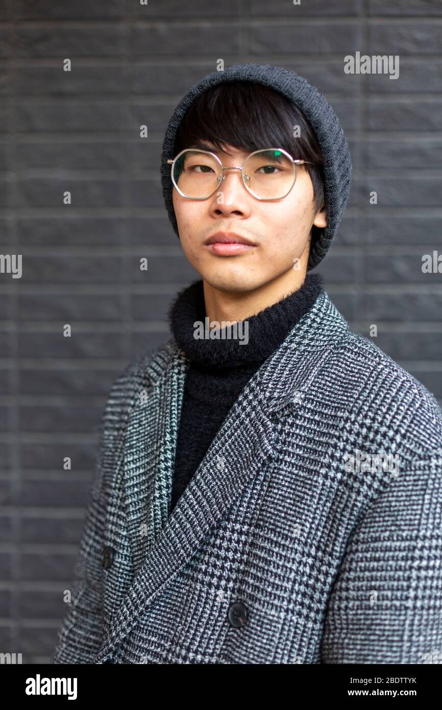 Attractive asian young man wearing coat, hat and glasses. Street fashion  concept Stock Photo - Alamy