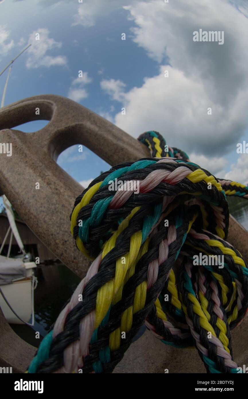 Close up of nautical rope used for boats tied to boat dock or steps of ladder attached to dock at cottage in summer on sunny day fun at cottage Stock Photo