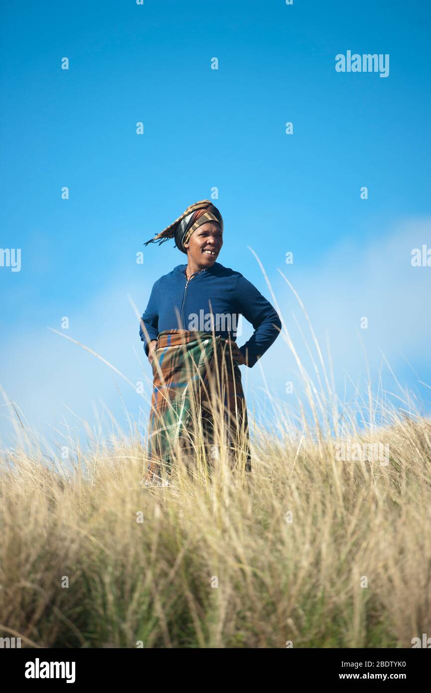 Woman smiling wearing rug in grass, Pondoland, Eastern Cape, Transkei, South Africa Stock Photo