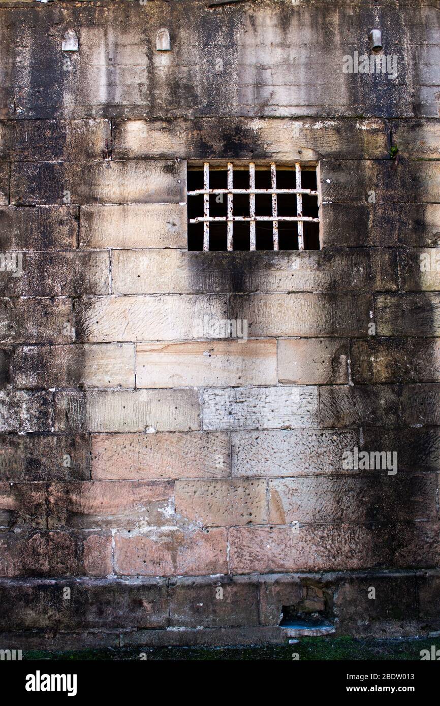 Historical sandstone convict built brick prison building, windows rusting security grill, wall background Stock Photo