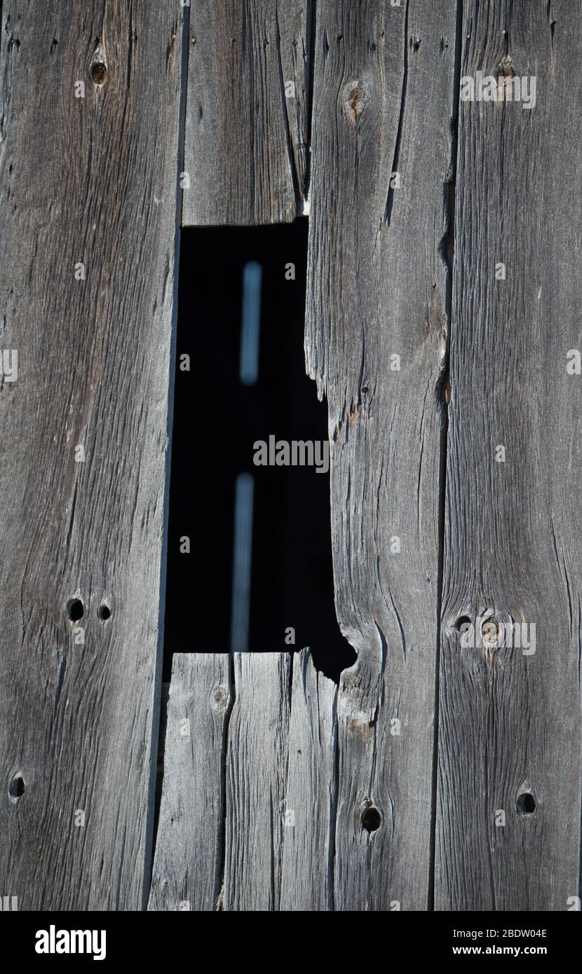 Dark Black Rectangular Shaped Opening of Window in Old Weathered Barn Board Rural Barn With vertical Slats of Grey Weathered Barn Board and Wood Knots Stock Photo