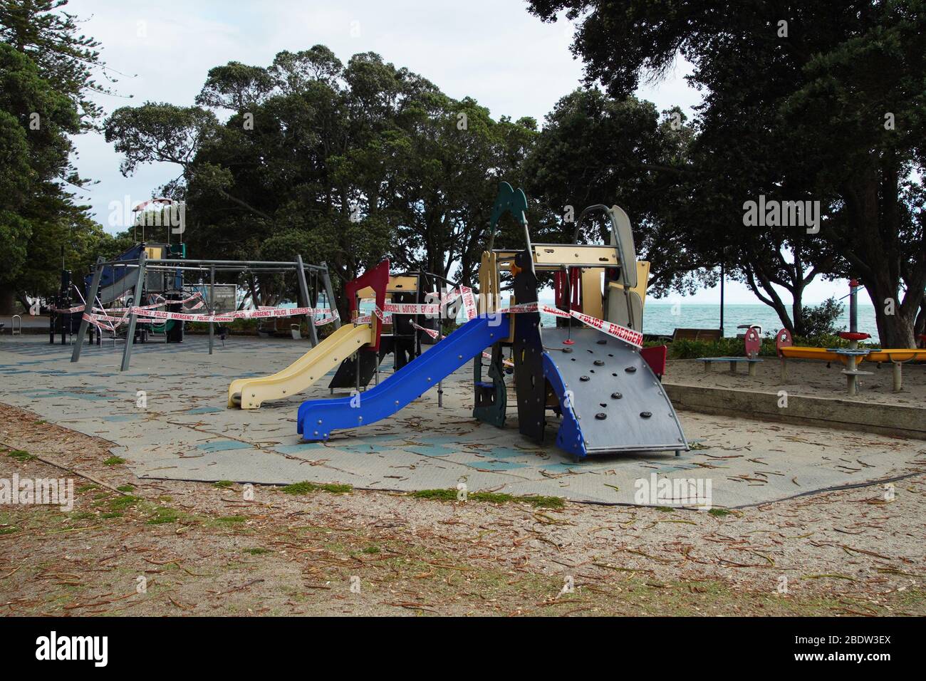 Red and white police emergency warning tape on outdoor children's playground equipment preventing use during the coronavirus lockdown.  Crime scene. Stock Photo