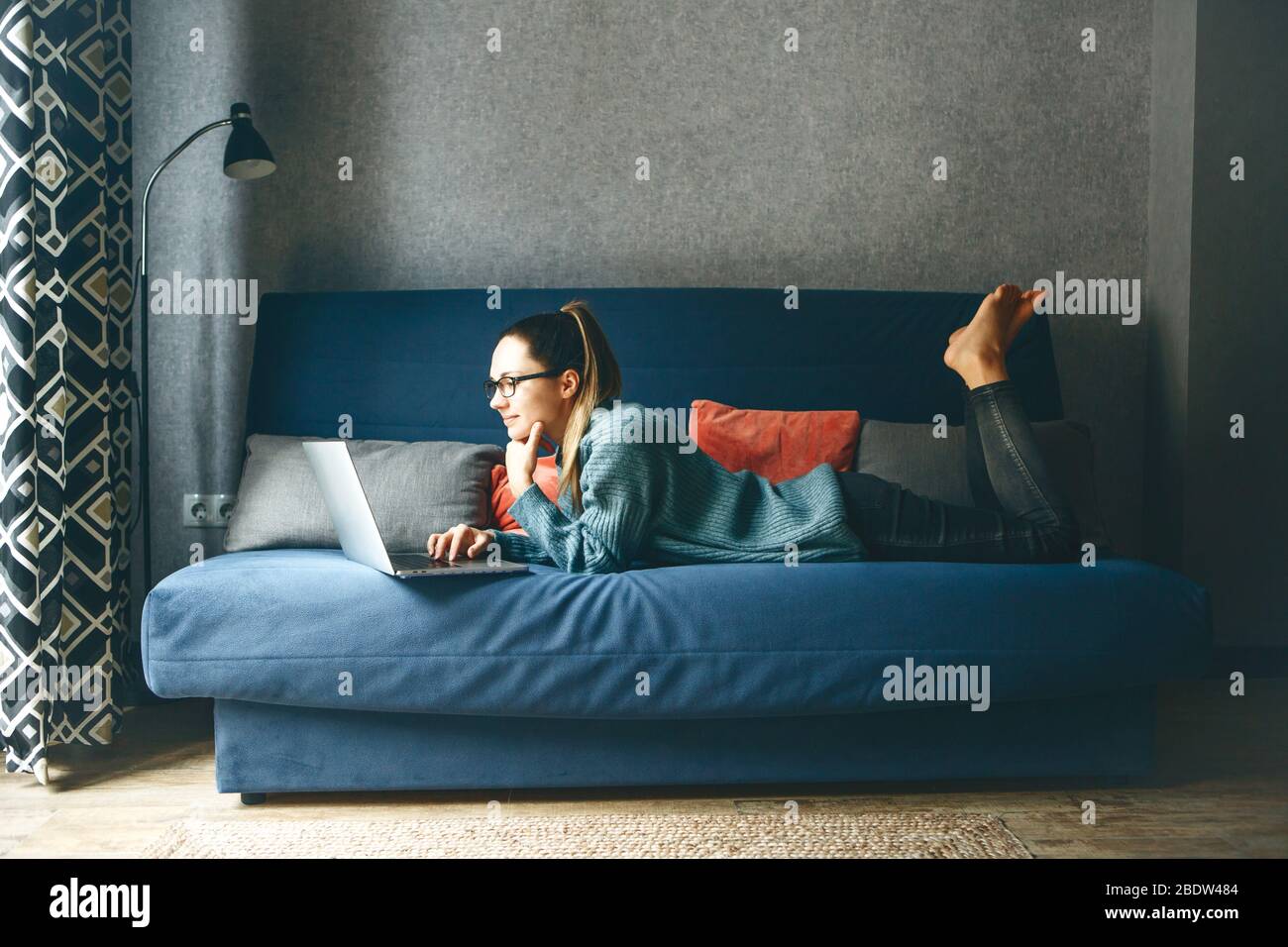 Girl working on laptop from home or student studying from home or freelancer. Or she is watching a video or using the Internet Stock Photo