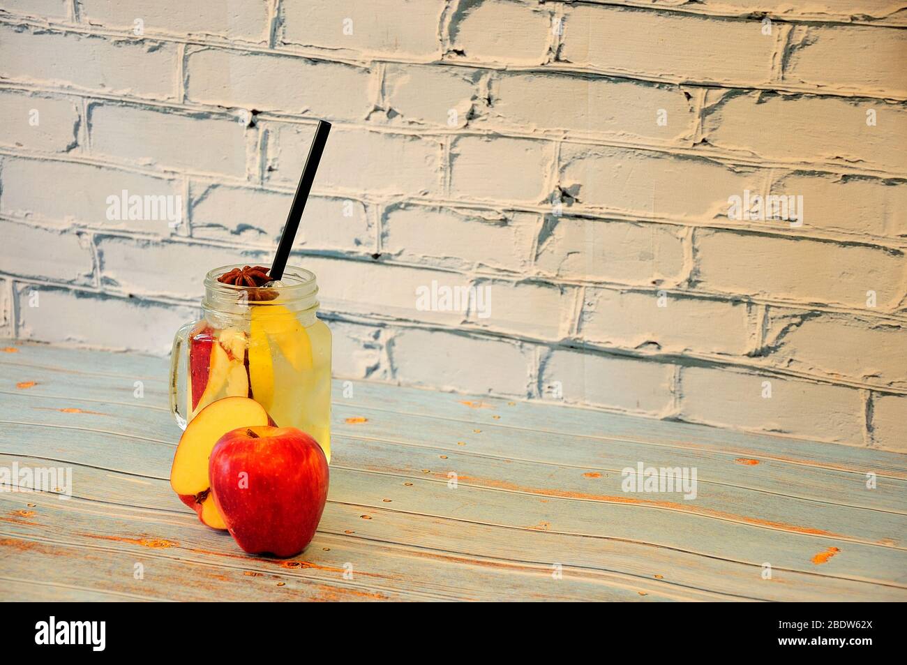Glass mug with a pen filled with juice with ice and apples on a wooden table. Close-up. Stock Photo