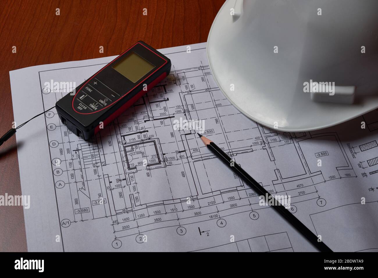 Laser meter, white hardhat and drawings at engineer workplace. Stock Photo