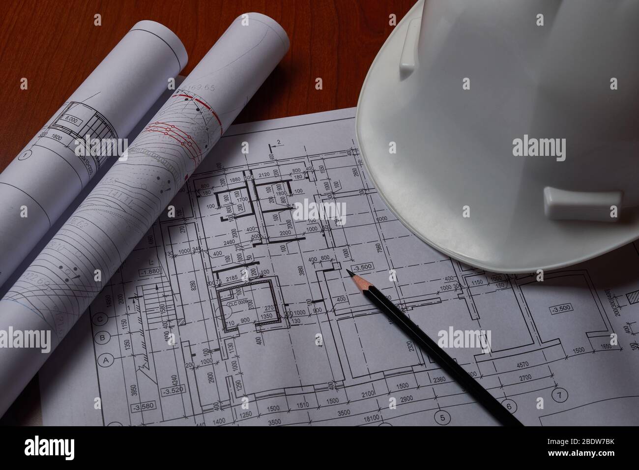White hardhat and drawings at engineer workplace. Stock Photo
