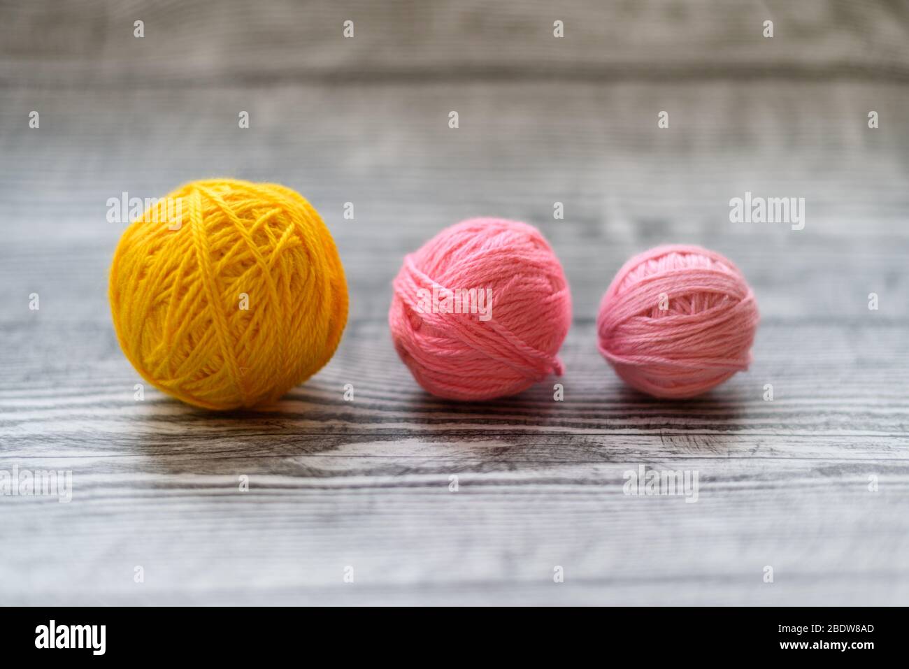 Three colred wool balls laying on the grey wooden background. Stock Photo