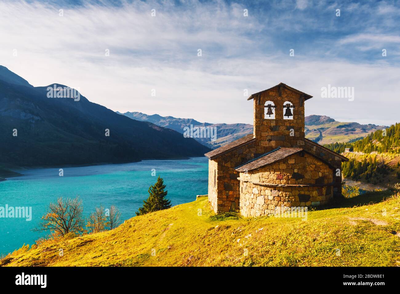 Sunny picturesque view of stone chapel on Roselend lake (Lac de Roselend) in France Alps (Auvergne-Rhone-Alpes). Landscape photography Stock Photo
