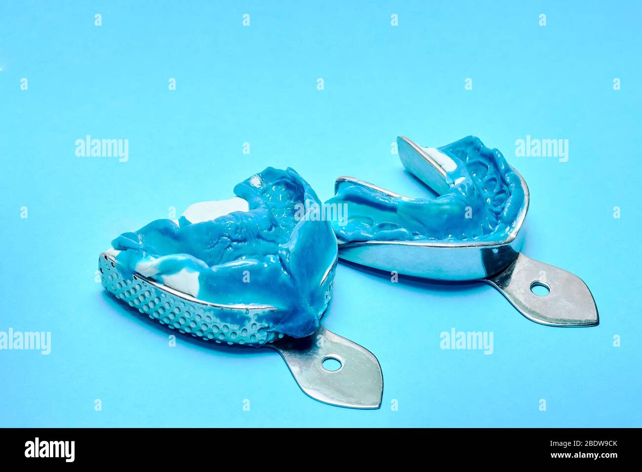 Two dental impressions on a blue background with copy space. Dental