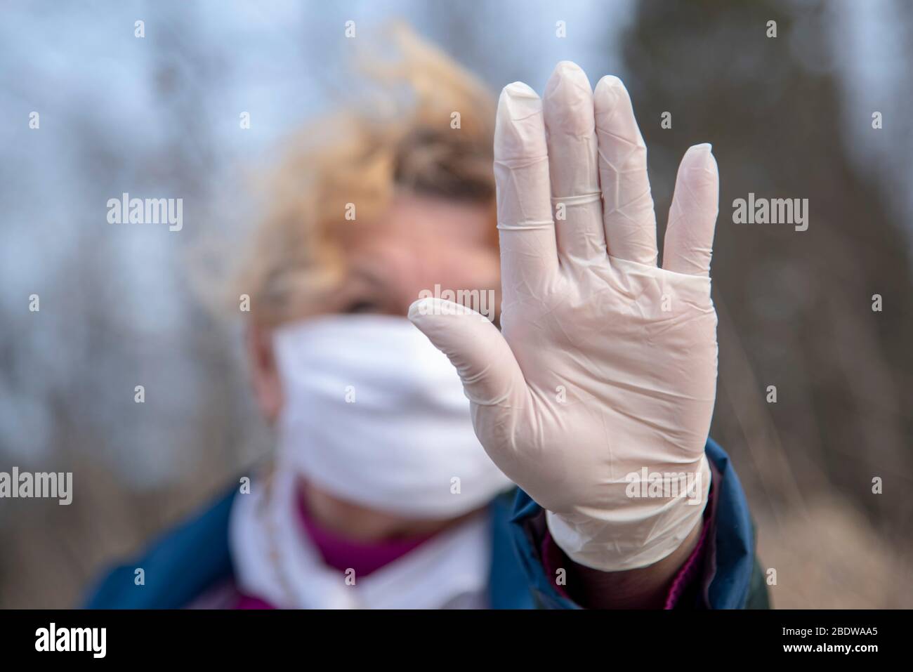 An elderly woman in a medical protective mask and rubber gloves gestures  stop coronavirus Stock Photo - Alamy