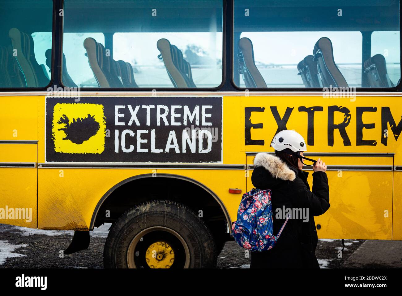 A tourist wearing winter clothes gets off the bus for a hike on Svinafellsjokull glacier an outlet glacier of Vatnajokull, South Iceland Stock Photo