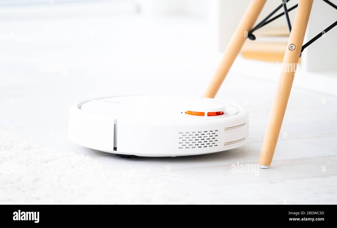 White robotic vacuum cleaner on a floor Stock Photo