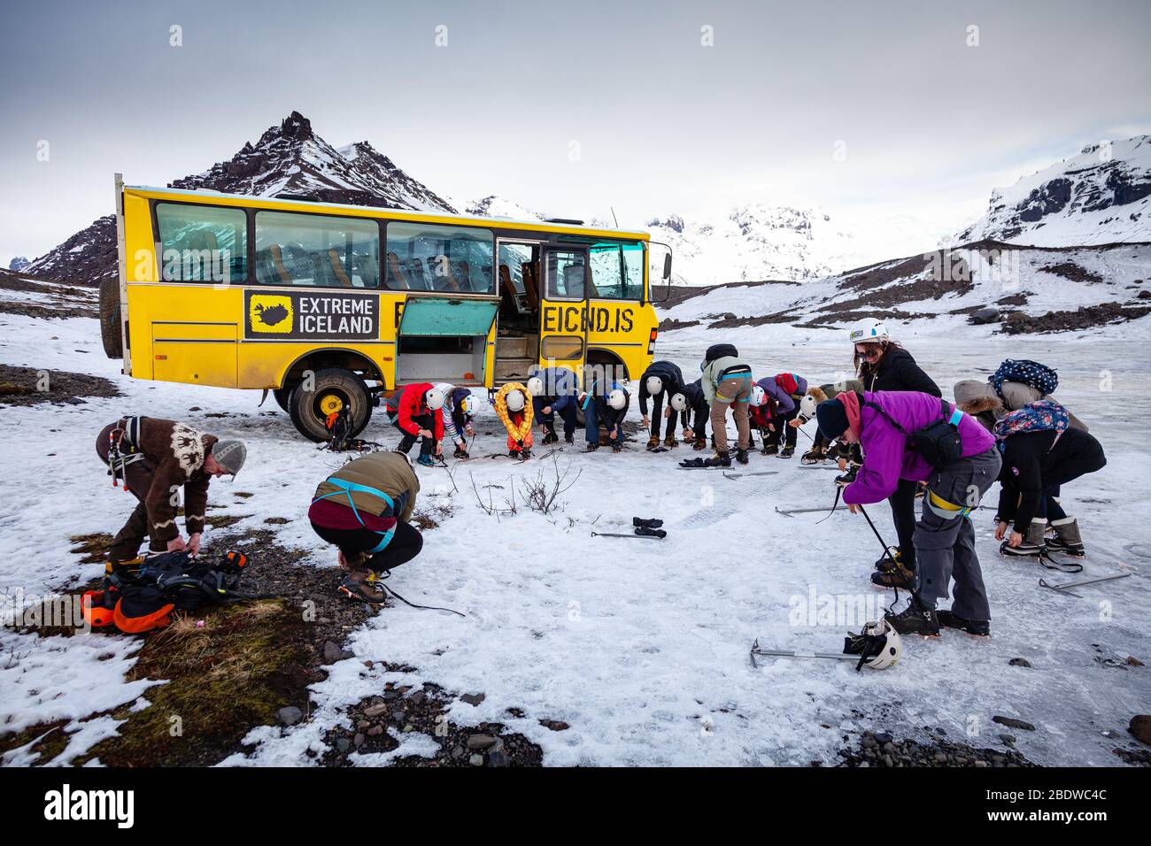 Tourists wearing protective clothing put on crampons for glacier hike on Svinafellsjokull glacier an outlet glacier of Vatnajokull, South Iceland Stock Photo