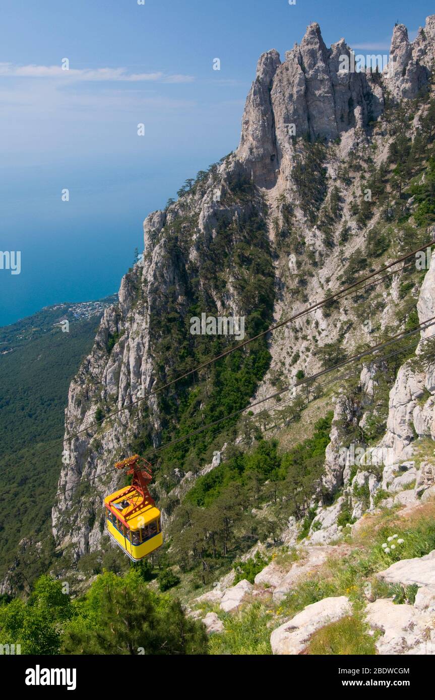 Bright yellow cable railway carriage is situated against the Ai-Petri ...
