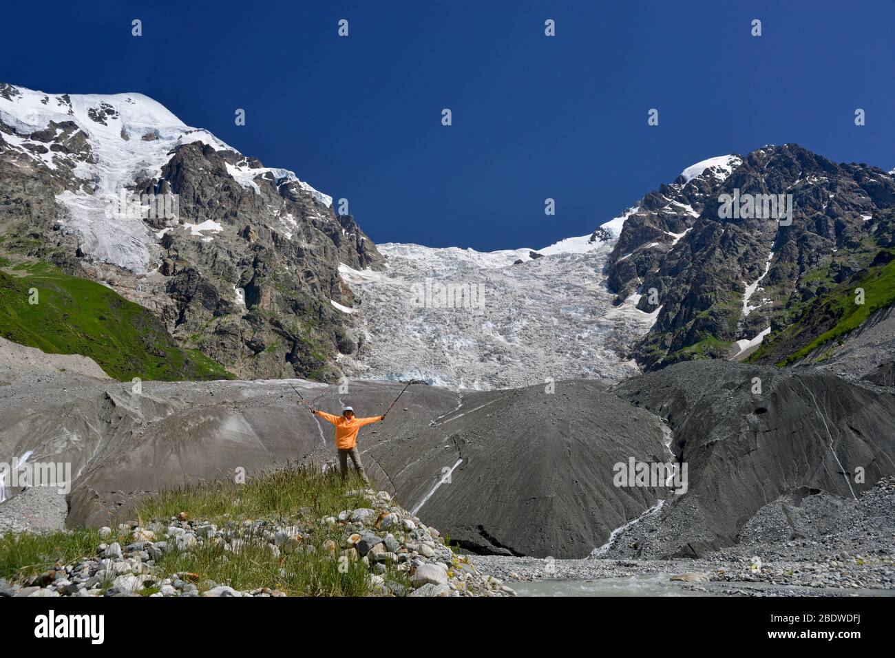 Happy tourist against large icefall background. Summer clear day and beautiful nature. Stock Photo