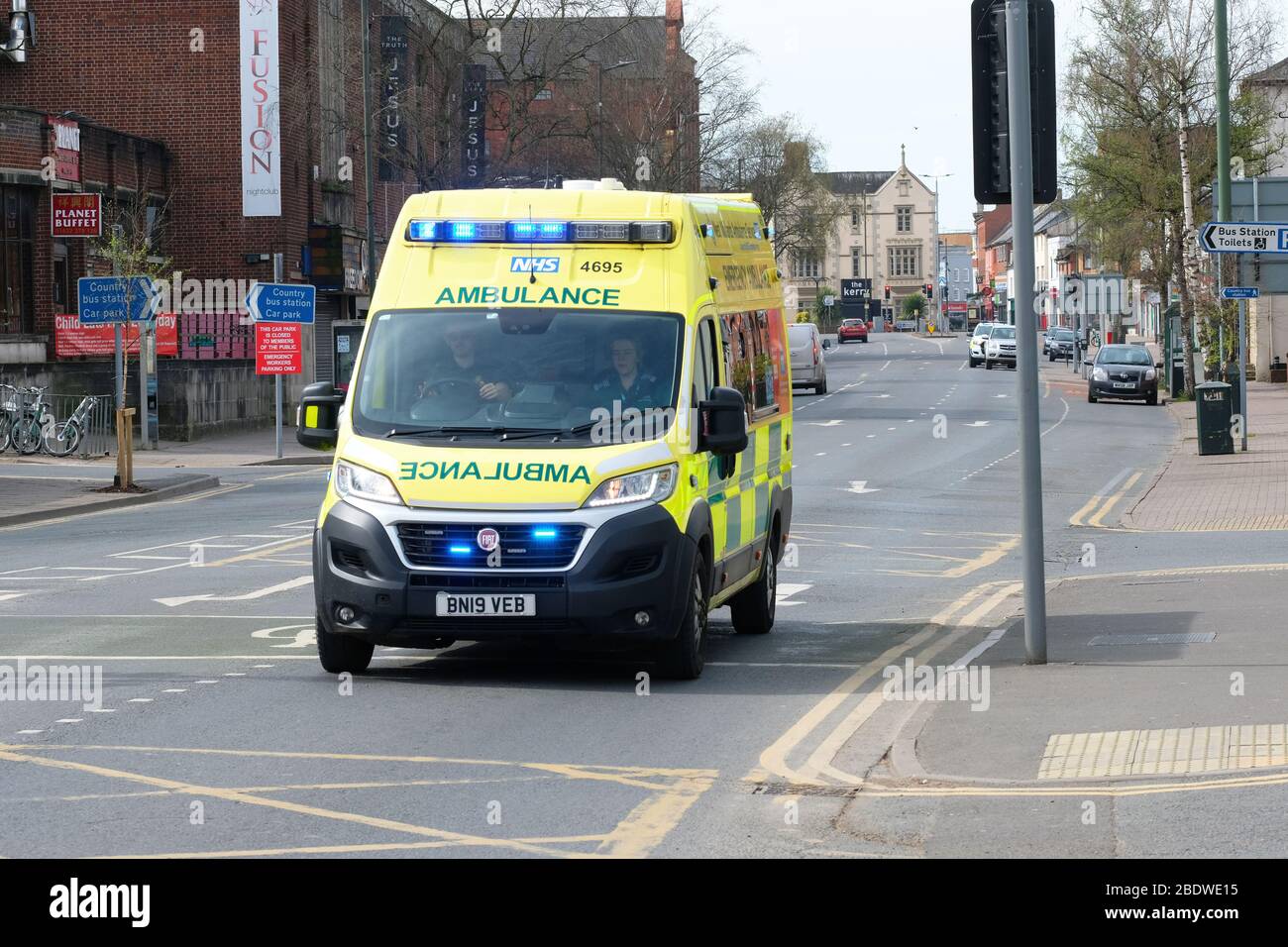 An emergency ambulance with blue lights flashing on near empty roads during the Coronavirus lockdown in Hereford UK Stock Photo