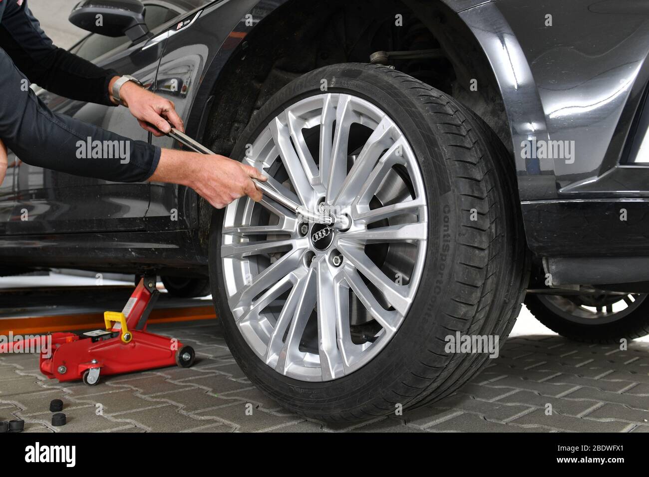 Grafing, Deutschland. 10th Apr, 2020. WINTER ON SUMMER TIRES Corona crisis  makes changing tires difficult. Change of wheels in the garage at home. Do  it yourself. The jack is attached. The wheel