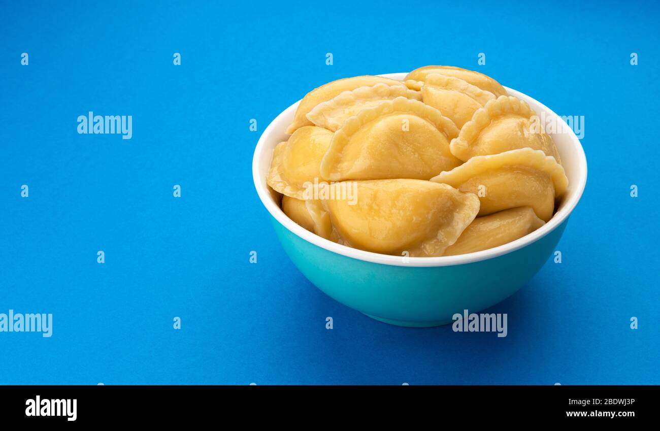 Filled dumplings, russian vareniki, pelmeni on blue background Stock Photo