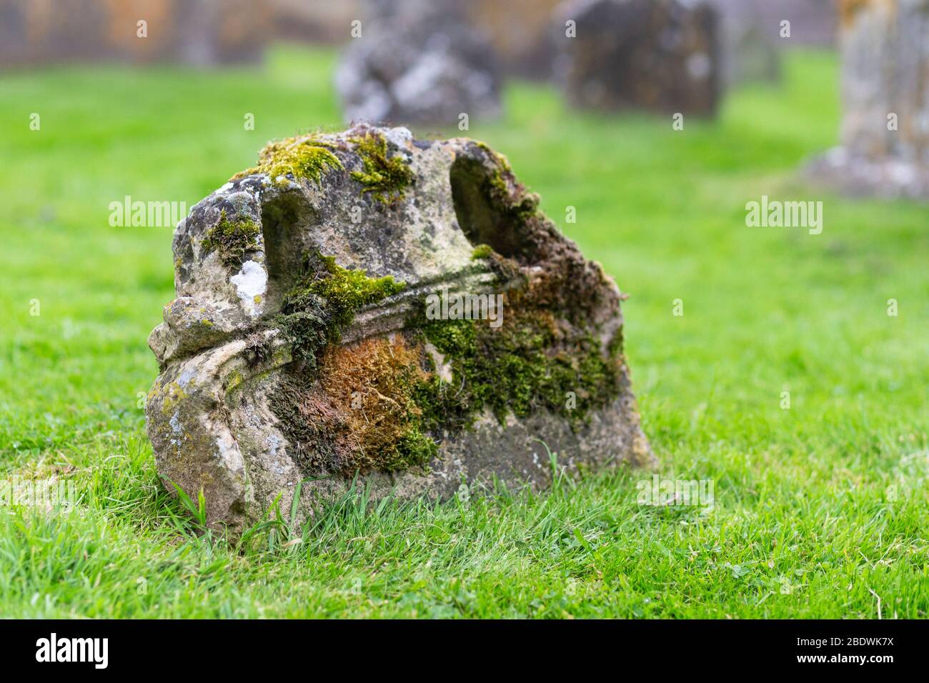 Overgrown gravestone at the Church of St Michael and All Angels in the village of Stanton in the Cotswolds, England Stock Photo